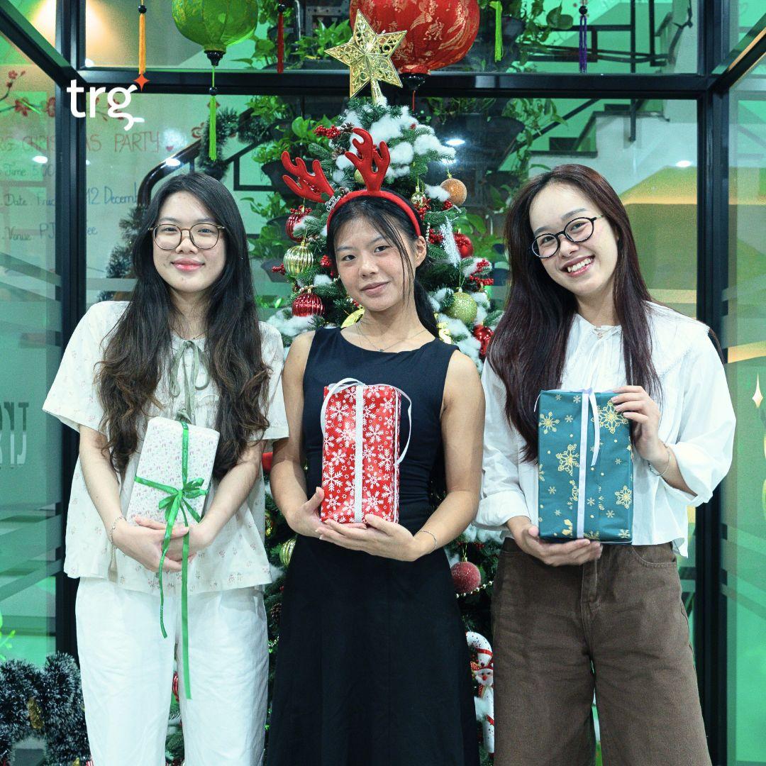 Three TRG interns holding gifts at a year-end celebration